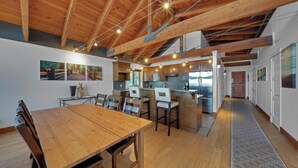 Un'ampia cucina con travi in legno, un'area pranzo con un grande tavolo in legno e un'isola centrale.