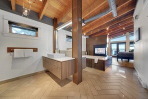 A modern kitchen with wooden beams, a large island, and a view of the living area.