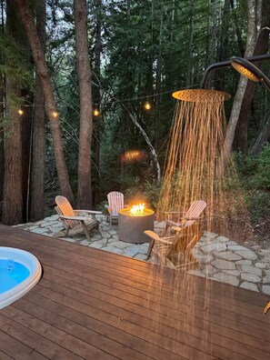 Une terrasse avec un foyer, des fauteuils Adirondack et un jacuzzi.