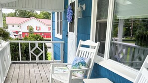 A wooden porch with white rocking chairs and a small table, blue walls, and a white railing. - Delightful, newly renovated, 3 bedroom cape in a charming country setting  (Marilla)