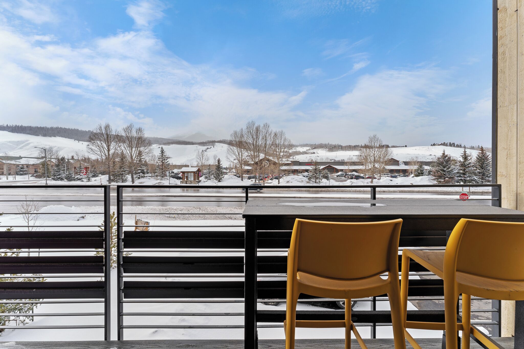 A dining area with a view of a snowy landscape, featuring a table and two chairs.