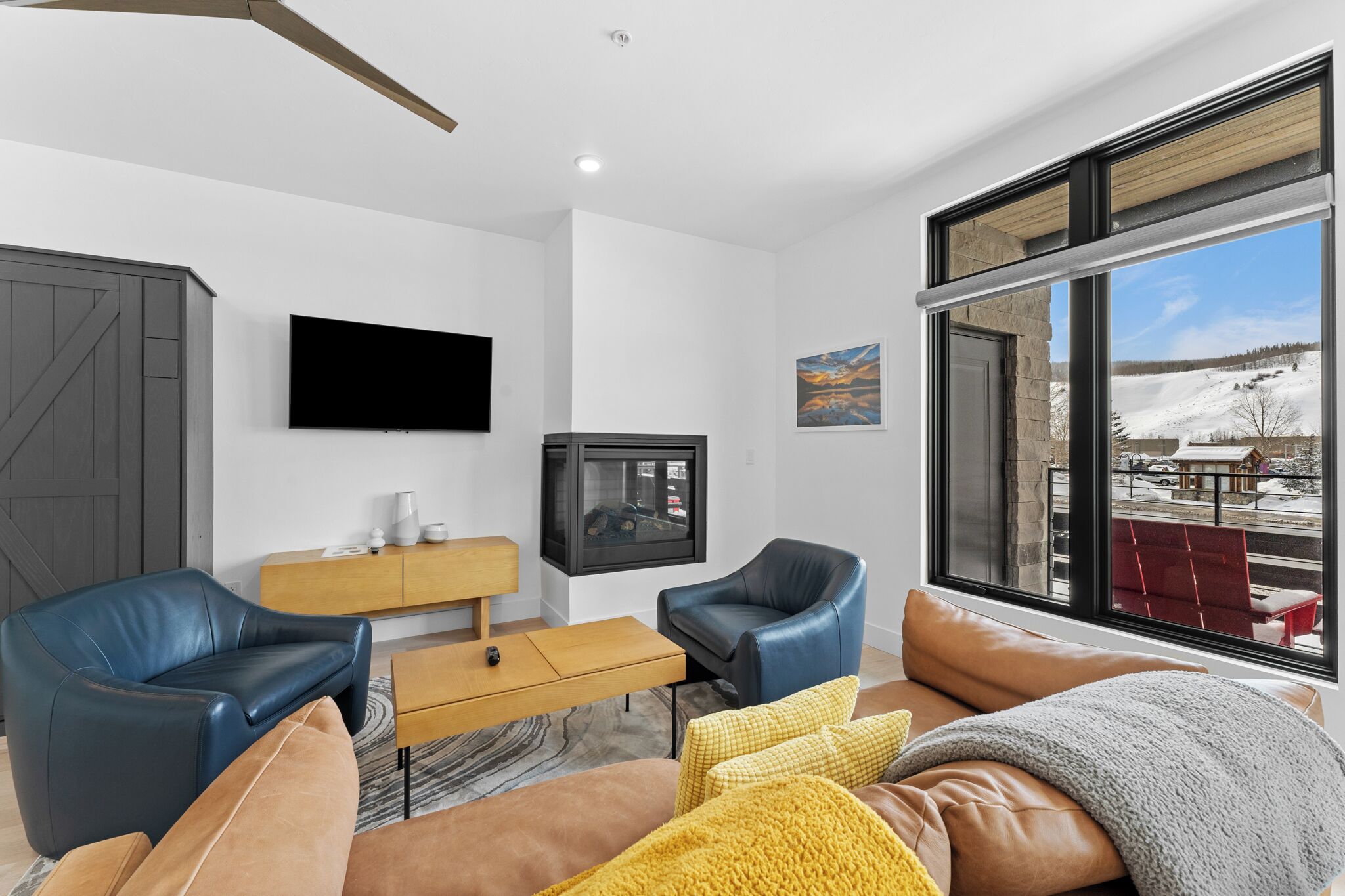 Ein modernes Wohnzimmer mit großem Fenster, Flachbildfernseher, Kamin und Ledersofas.