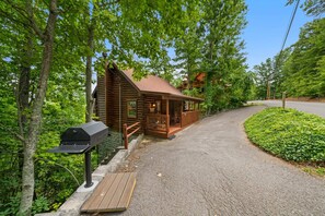 A wooden cabin with a porch and a barbecue grill.