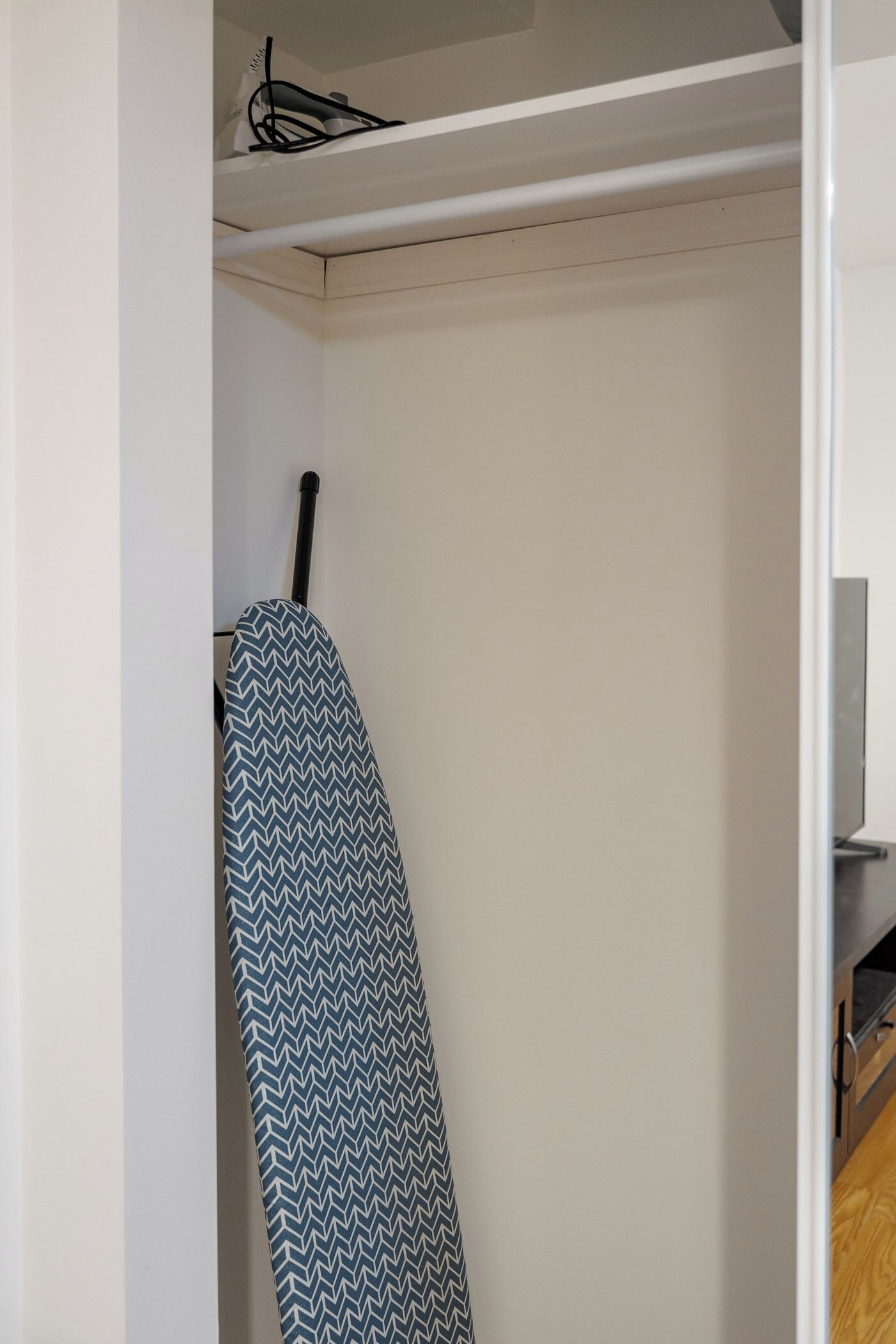 Un armario con un planchador colgado y una puerta de madera.