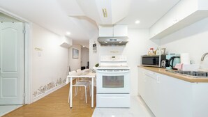 Una cocina moderna con armarios blancos, horno empotrado, microondas y cafetera.