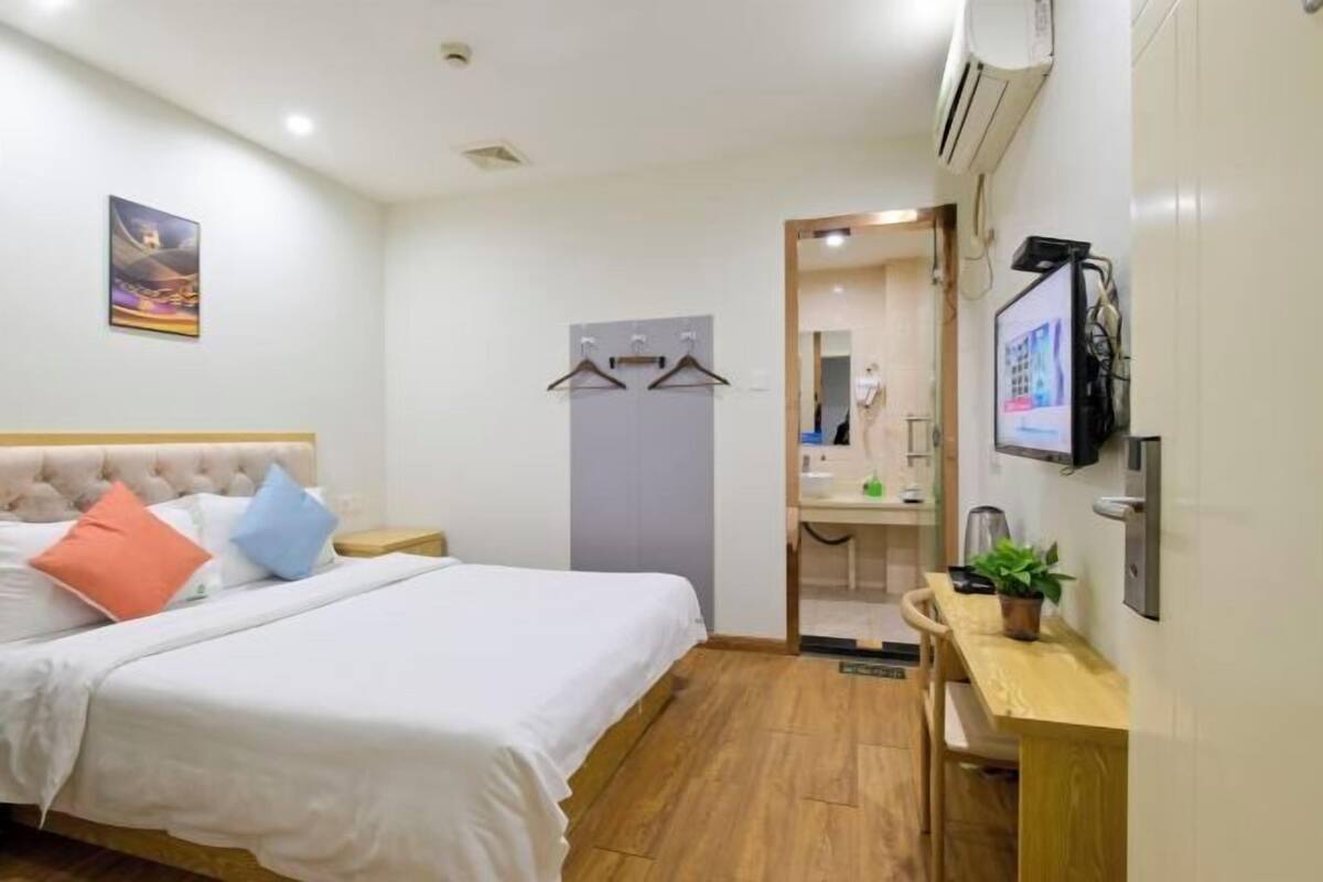 Una habitación de hotel con cama, mesita de noche y escritorio con silla.