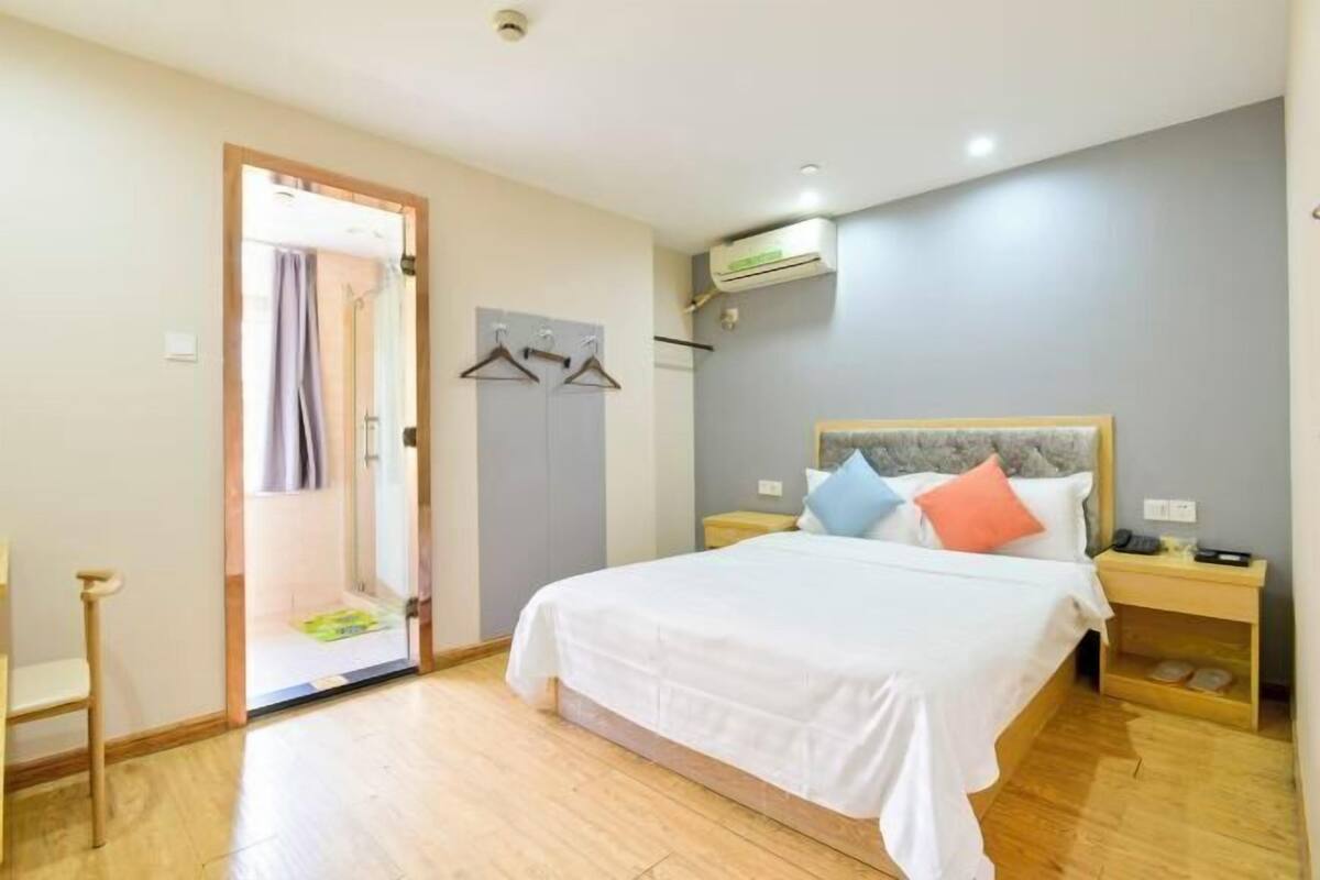 Un dormitorio con cama, mesitas de noche, armario y equipo de aire acondicionado.
