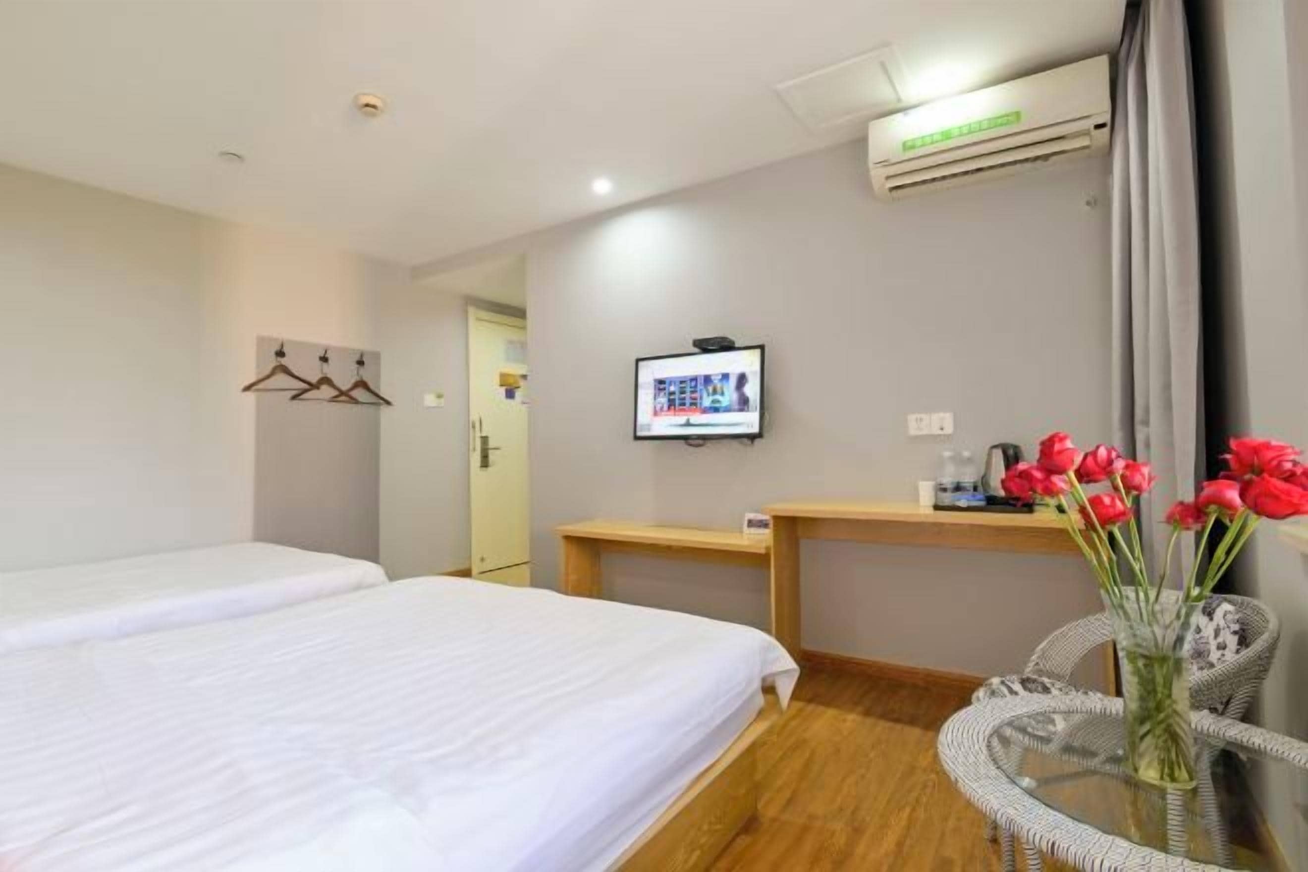 Een hotelkamer met twee bedden, een televisie, een bureau en een stoel met een bloevas.