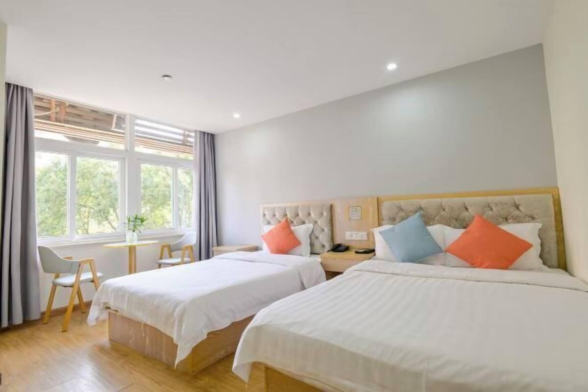 Habitación de hotel con dos camas, un escritorio y una ventana con cortinas.