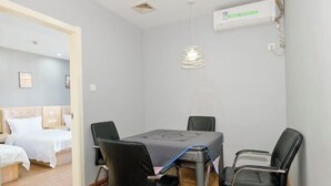 Ένα δωμάτιο με ένα κρεβάτι, ένα τραπέζι με καρέκλες, ένα φωτιστικό που κρέμεται από την οροφή και μια μονάδα κλιματισμού.