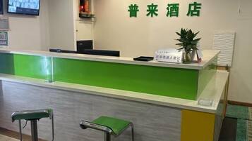 Ein Empfangstresen mit Grün-Weiß-Design, ein an der Wand befestigter Fernseher und ein Schild mit chinesischen Schriftzeichen.