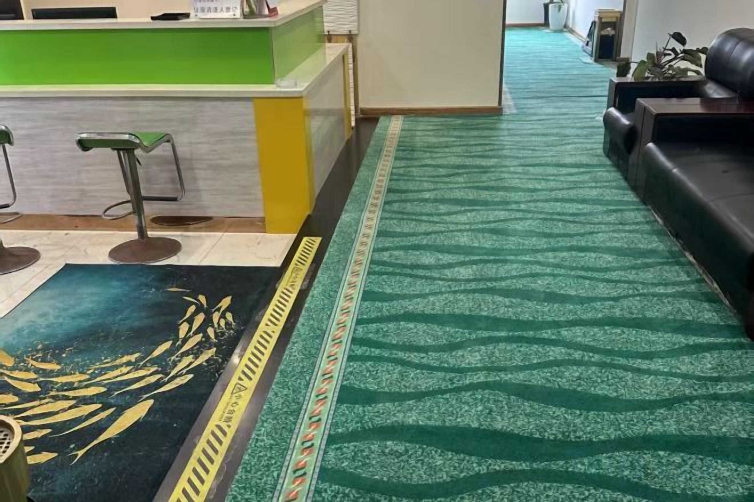 A reception area with a green counter, a patterned carpet, and a sofa.