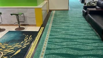 A reception area with a green counter, a patterned carpet, and a sofa.