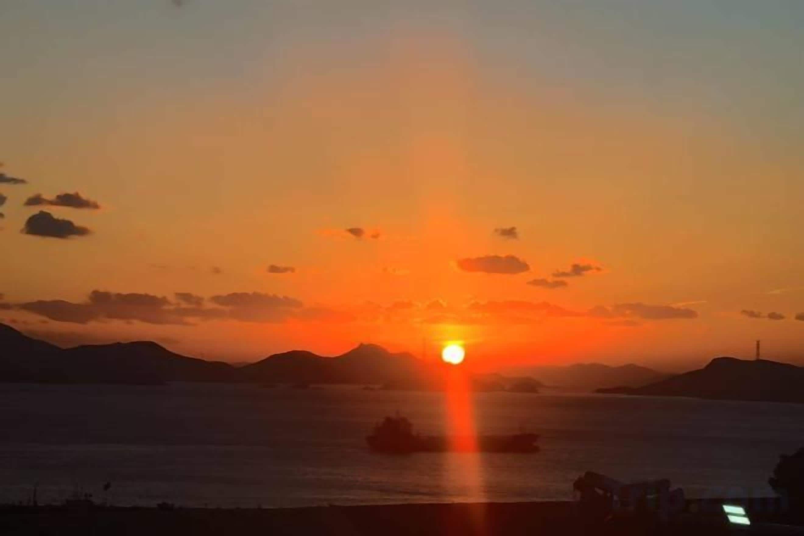 Un atardecer sobre una masa de agua con tierras a lo lejos.