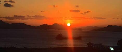 Un atardecer sobre una masa de agua con tierras a lo lejos.