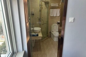 Un baño con ducha de vidrio, lavamanos e inodoro.