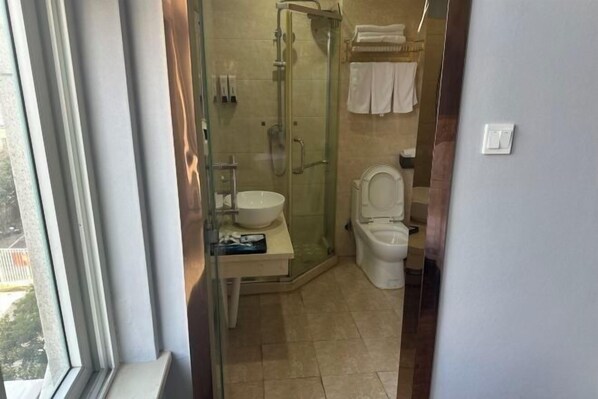 Un baño con ducha de vidrio, lavamanos e inodoro.