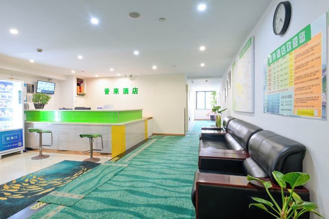 A reception area with a green counter, a reception desk, a seating area with a sofa and chairs, and a patterned carpet.