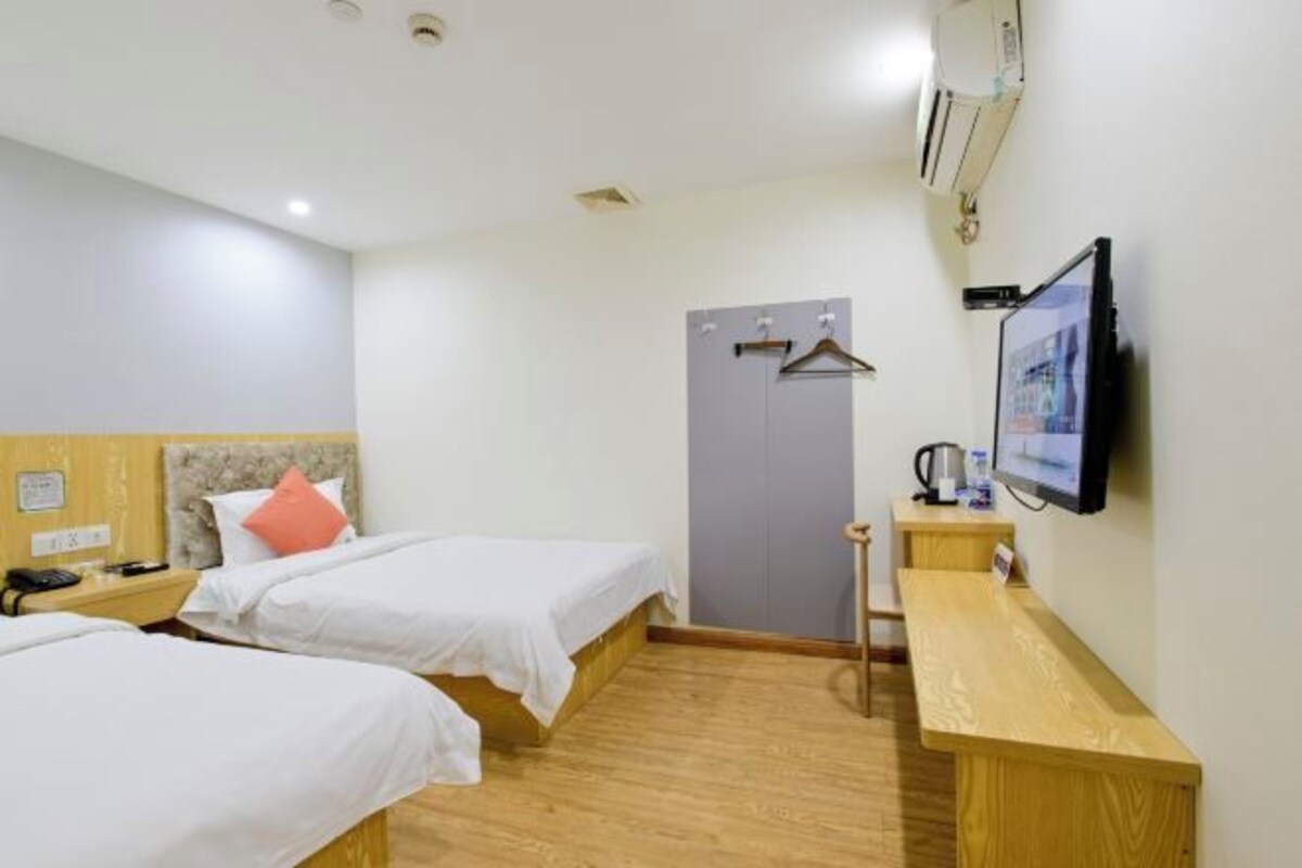 Habitación de hotel con dos camas, un escritorio, un televisor y un armario.
