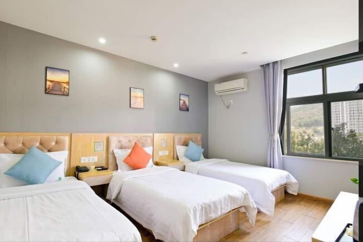 Habitación de hotel con dos camas, un escritorio, ventana con vistas y un equipo de aire acondicionado.
