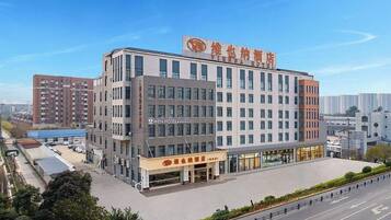 A multi-story hotel with a modern architectural design, featuring a prominent entrance and a parking area.