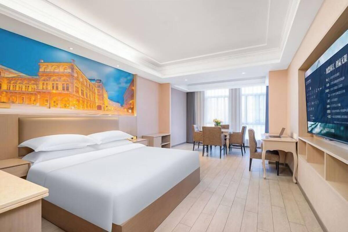 A hotel room with a large bed, a desk, and a TV.