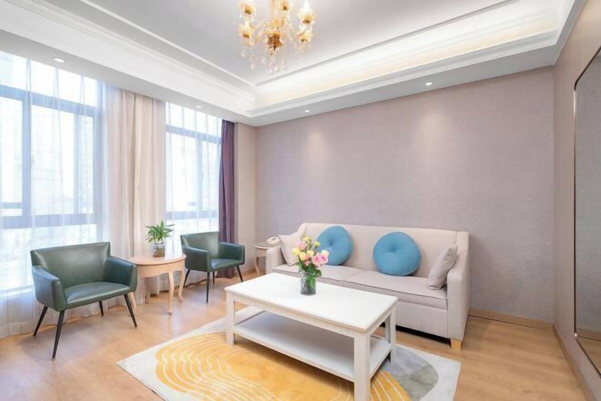 A modern living room with a sofa, two armchairs, a coffee table, and a chandelier.