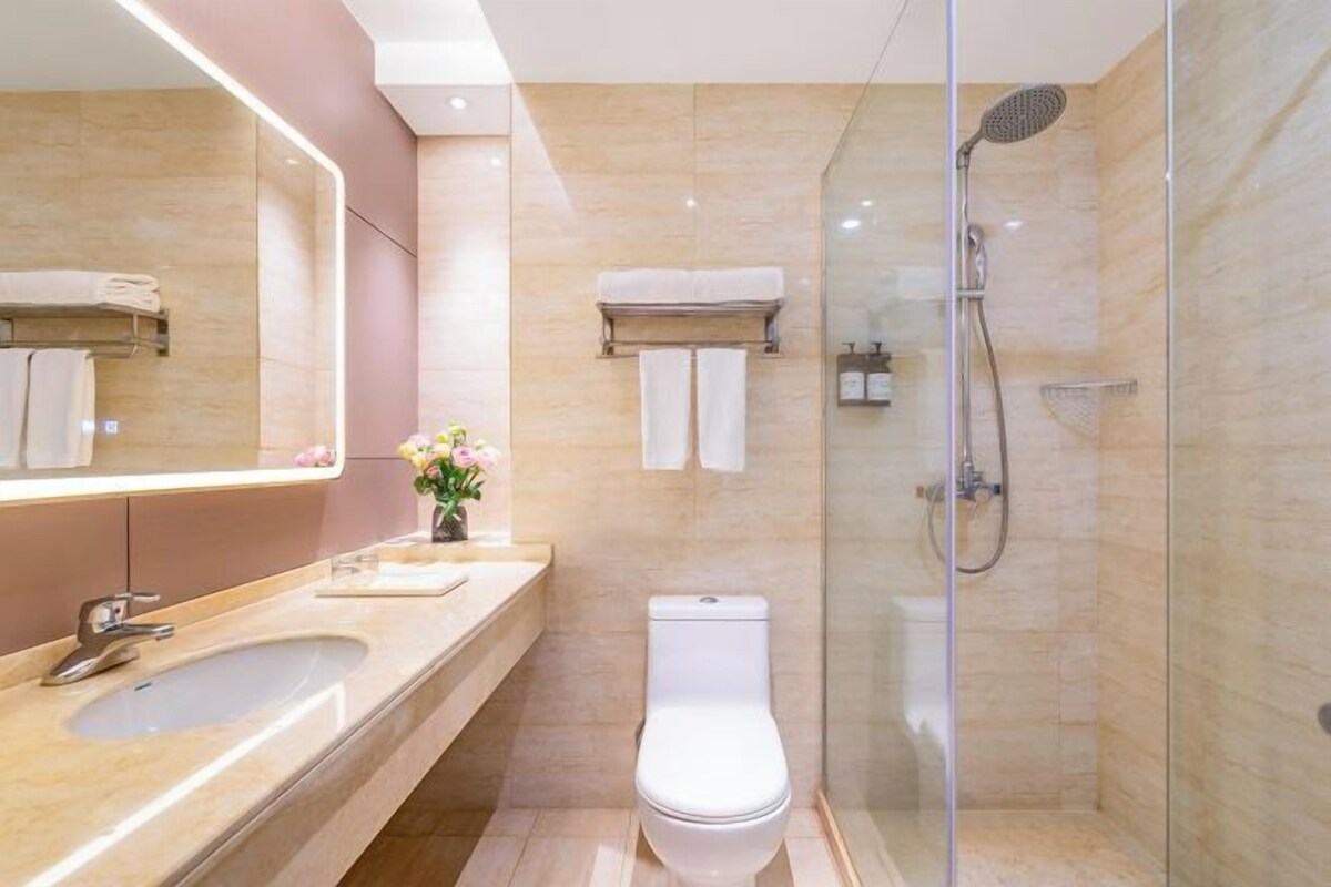 A modern bathroom with a glass-enclosed shower, a large mirror, and a vanity with a sink and towel rack.