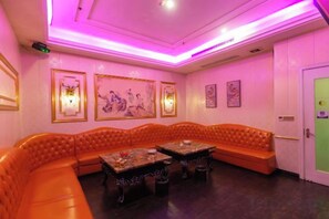 A room with a large orange leather sofa, two tables, and wall-mounted lights. - Wufeng International Hotel (Wufeng)