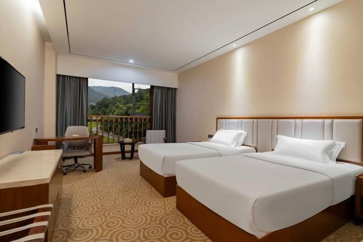 Una habitación de hotel con dos camas, un escritorio, una silla y un televisor.