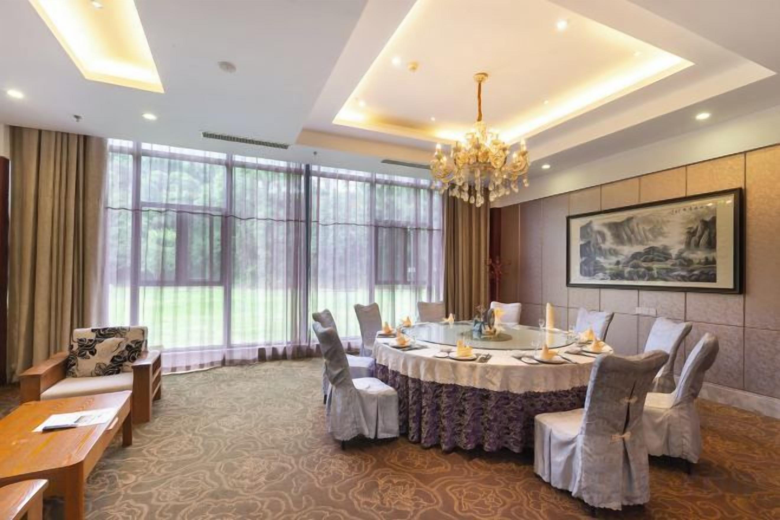 A conference room with a round table, chairs, and a chandelier.