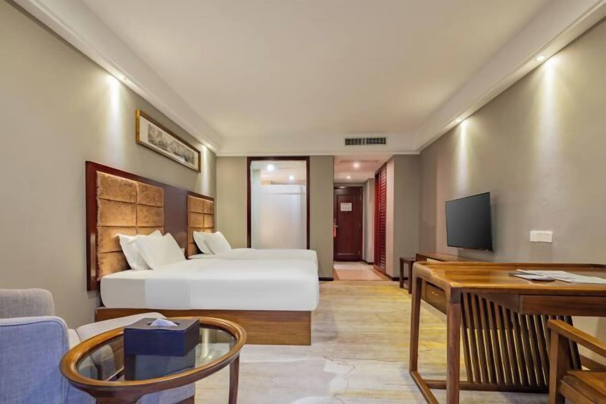 Habitación de hotel con cama, escritorio, silla, televisor y un cuadro en la pared.