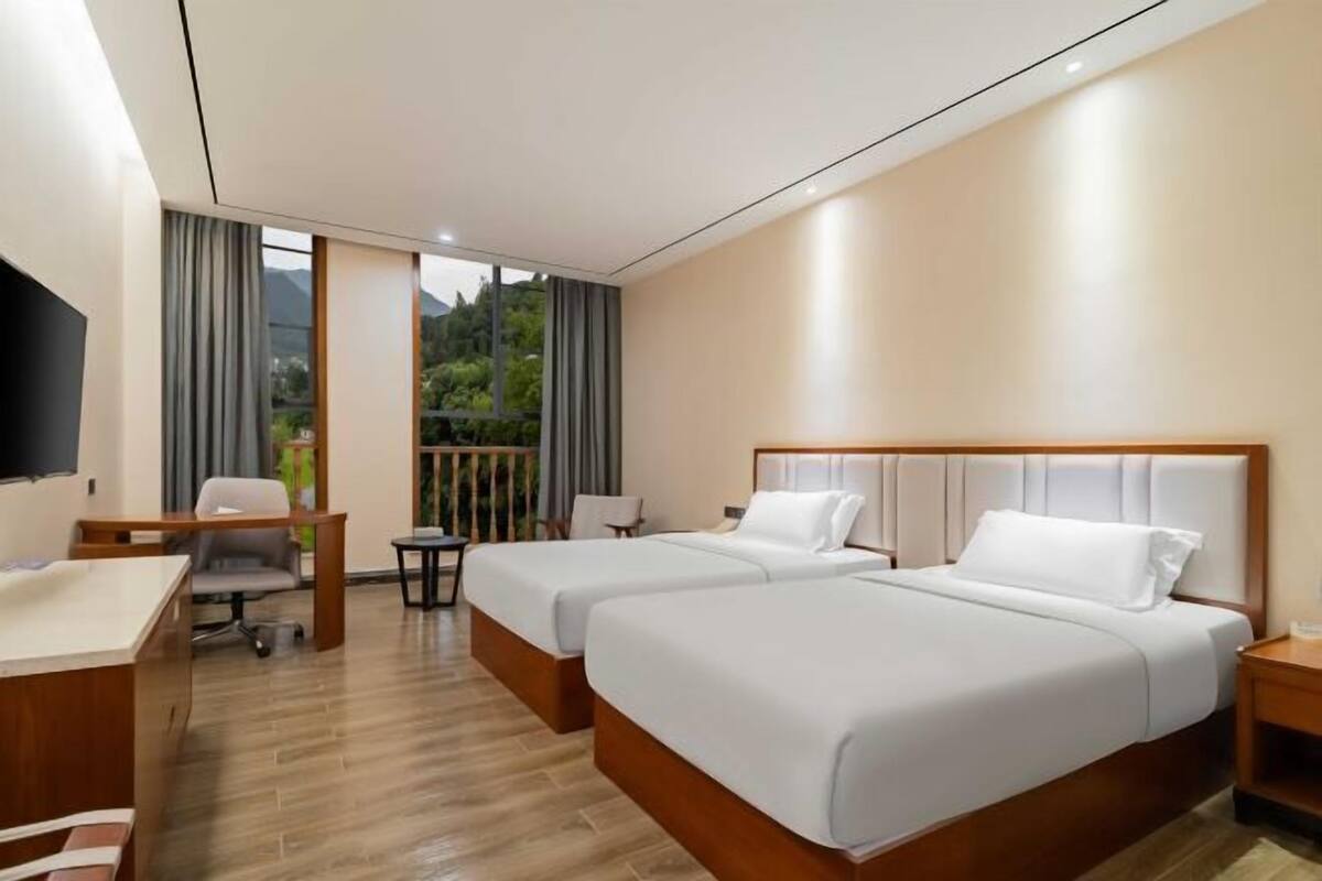 Una habitación de hotel con dos camas, un escritorio, una silla y un televisor.