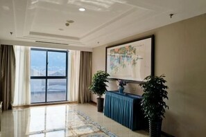 A spacious room with a large window, a blue console table, and a framed map on the wall. - Wufeng International Hotel (Wufeng)
