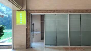 A hotel lobby with a sliding glass door entrance, a reception desk, and a yellow sign on the wall.