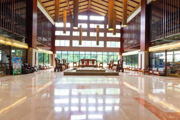 A spacious lobby with a high ceiling, large windows, and a central seating area.