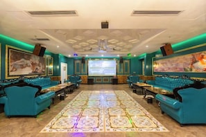 A spacious room with a large screen, seating area, and a patterned floor.