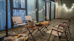 An outdoor seating area with chairs, a table with food, and string lights. - Wufeng International Hotel (Wufeng)