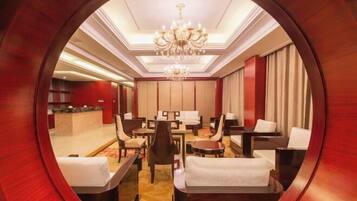 Um saguão de hotel com uma moldura de madeira redonda, um candelabro, disposição de assentos e um balcão de recepção.