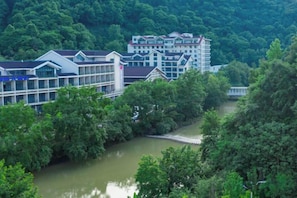 A riverside hotel with multiple buildings, a bridge, and dense greenery.