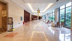 A spacious hotel lobby with a polished marble floor, a central chandelier, and seating areas with large windows offering a view of greenery. - Wufeng International Hotel (Wufeng)