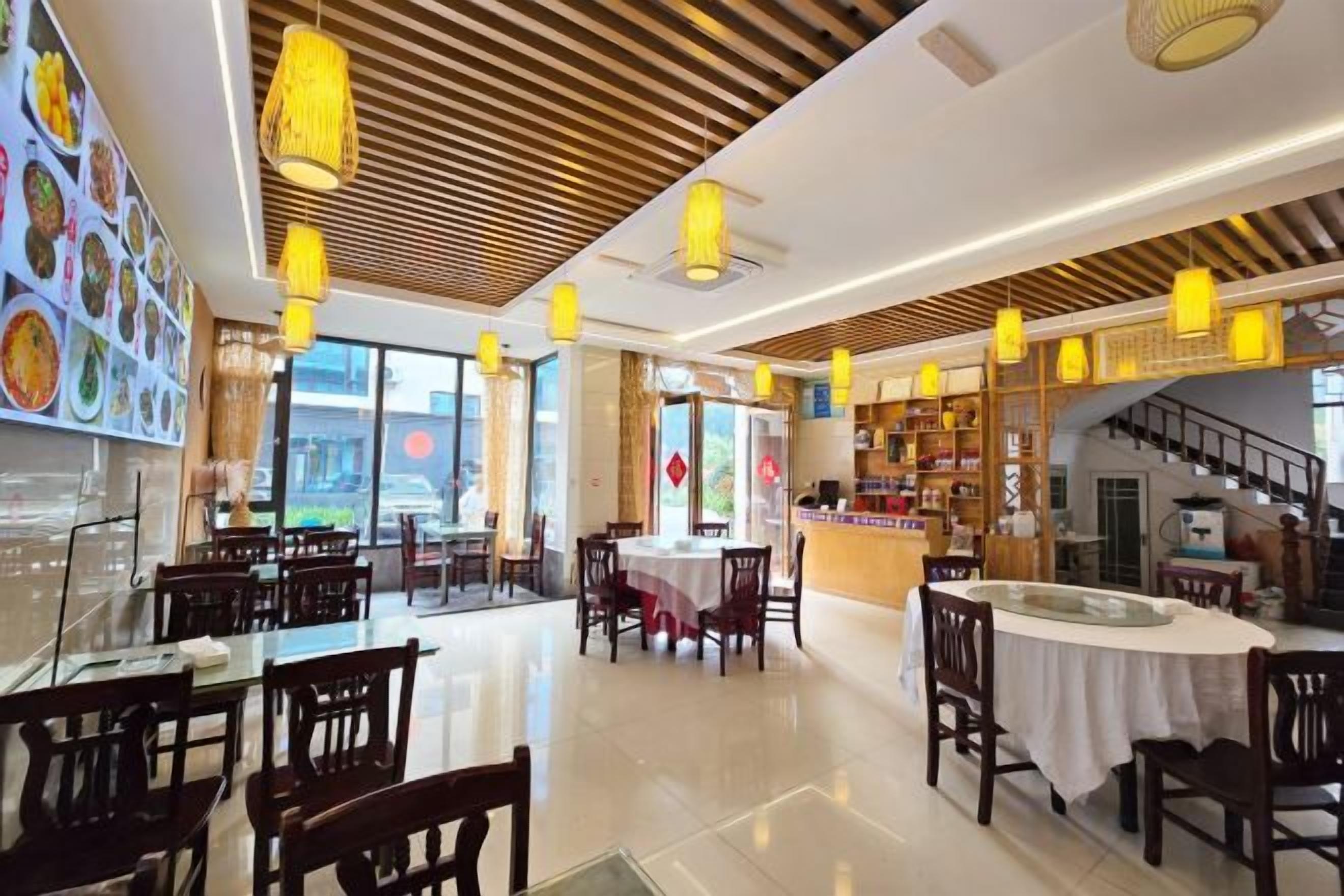 A restaurant with multiple dining tables, hanging lights, and a view of the city.