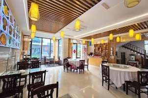 Un restaurante con varias mesas, luces colgantes y vistas a la ciudad.