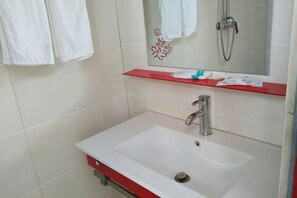 Un baño con un lavamanos blanco, un estante rojo y un espejo encima.