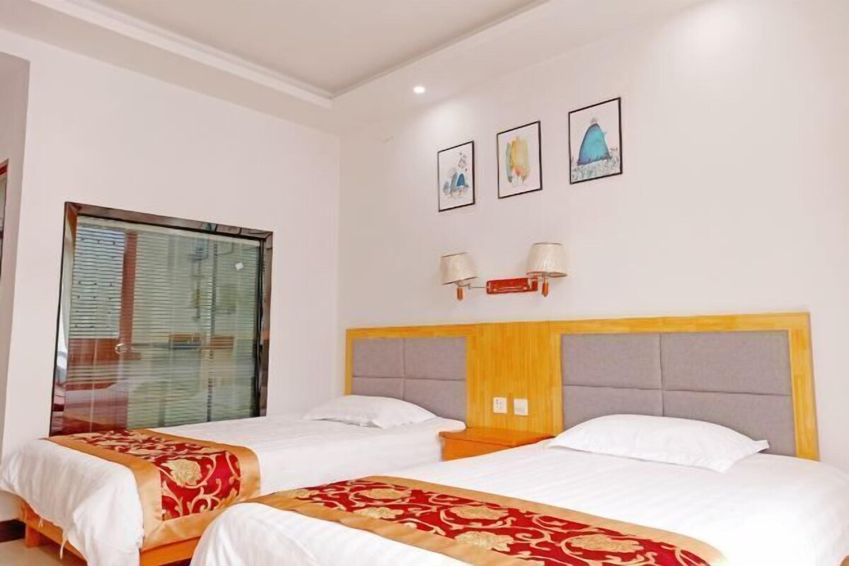 Een hotelkamer met twee bedden, een groot raam en kunstwerken aan de muur.