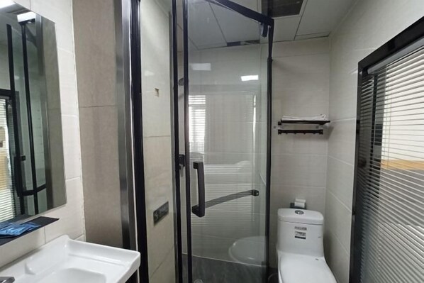 Een moderne badkamer met een douchecabine van glas, een wit wastafelmeubel en een toilet.