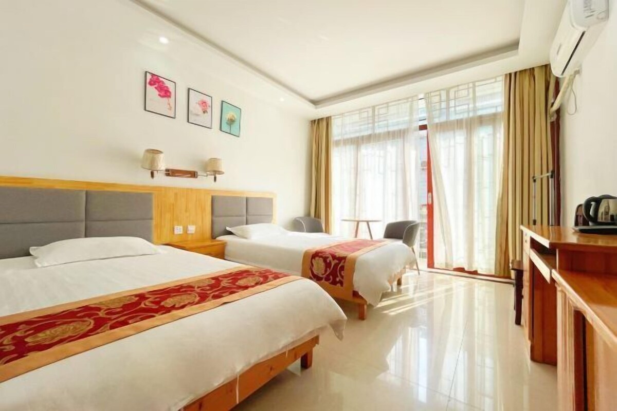 Een hotelkamer met twee bedden, een bureau, een stoel en een raam met gordijnen.