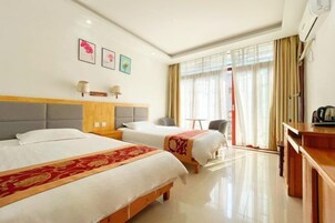 A hotel room with two beds, a desk, a chair, and a window with curtains.