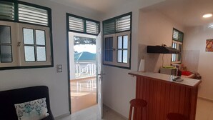 A compact kitchen with a wooden counter, a refrigerator, and a sink. There is a door leading to an outdoor area with a balcony. - Residence KAYA, Marie-Galante, sea view (Grand-Bourg)