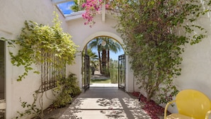 Un sendero que lleva a una puerta con vista a una palmera y un cielo despejado.